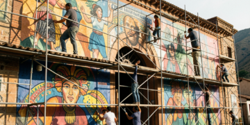 Artistas plásticos orureños trabajando en murales de gran formato sobre andamios en el Teatro Internacional Oruro.