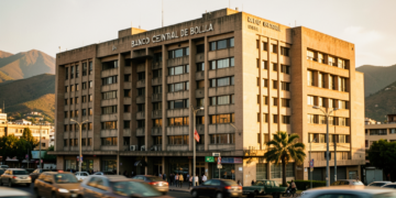 Fachada del Banco Central de Bolivia en La Paz con gráficos financieros superpuestos y movimiento urbano.